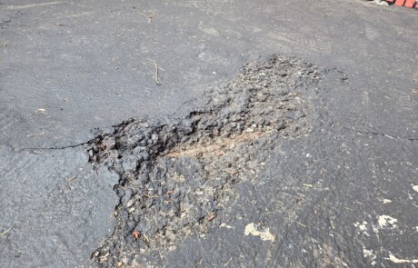 Damaged asphalt in dumpster enclosure